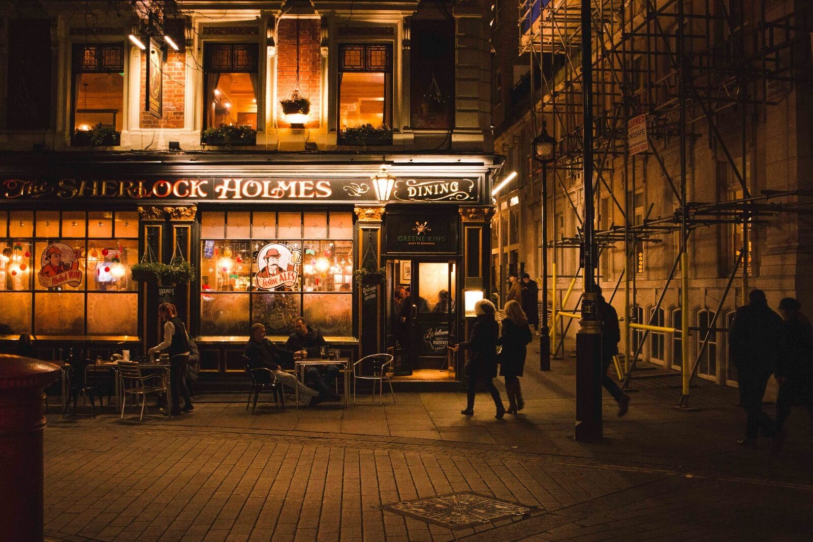 The Sherlock Holmes pub glowing on a London street at night