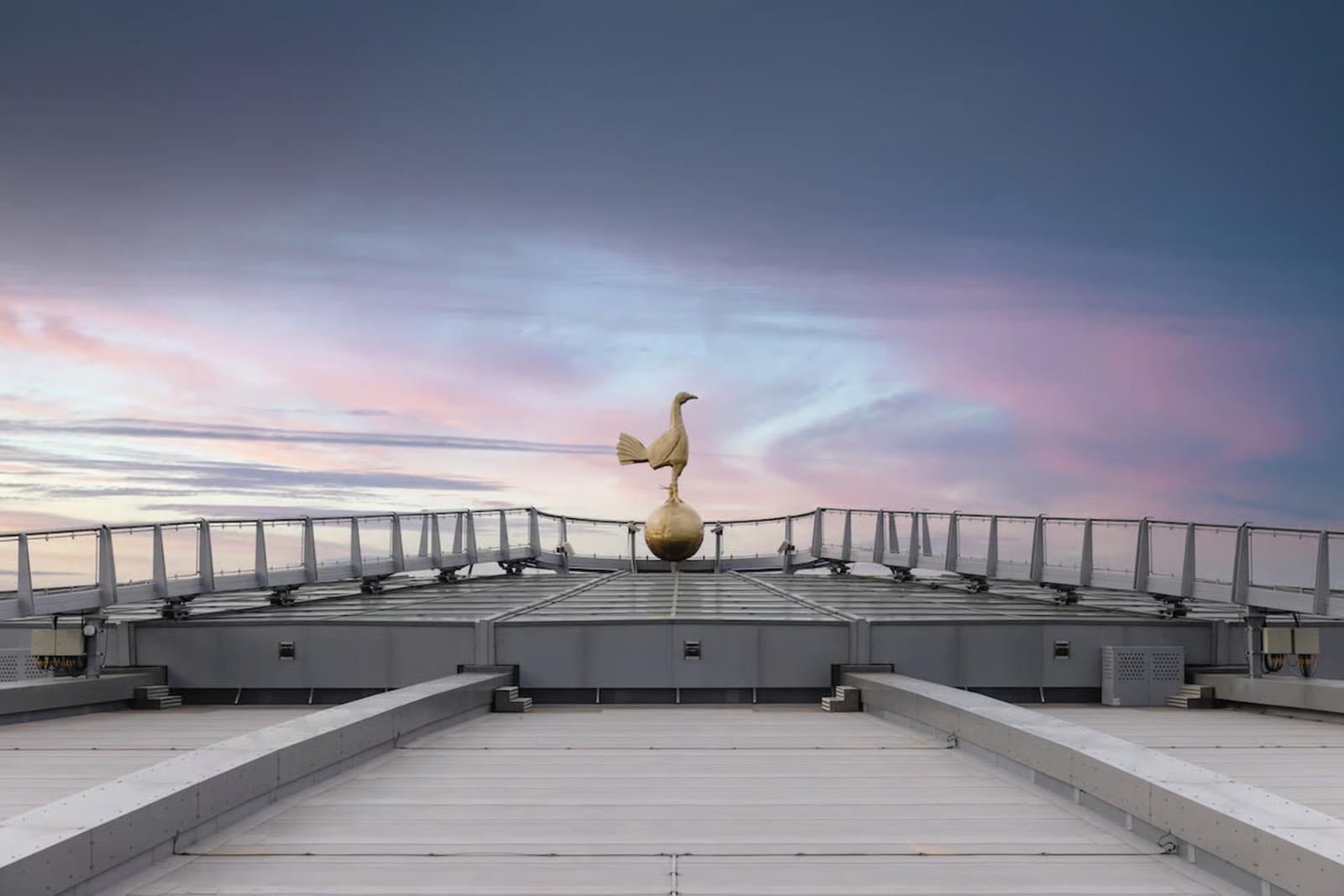 Golden cockerel atop Tottenham Hotspur Stadium at sunset